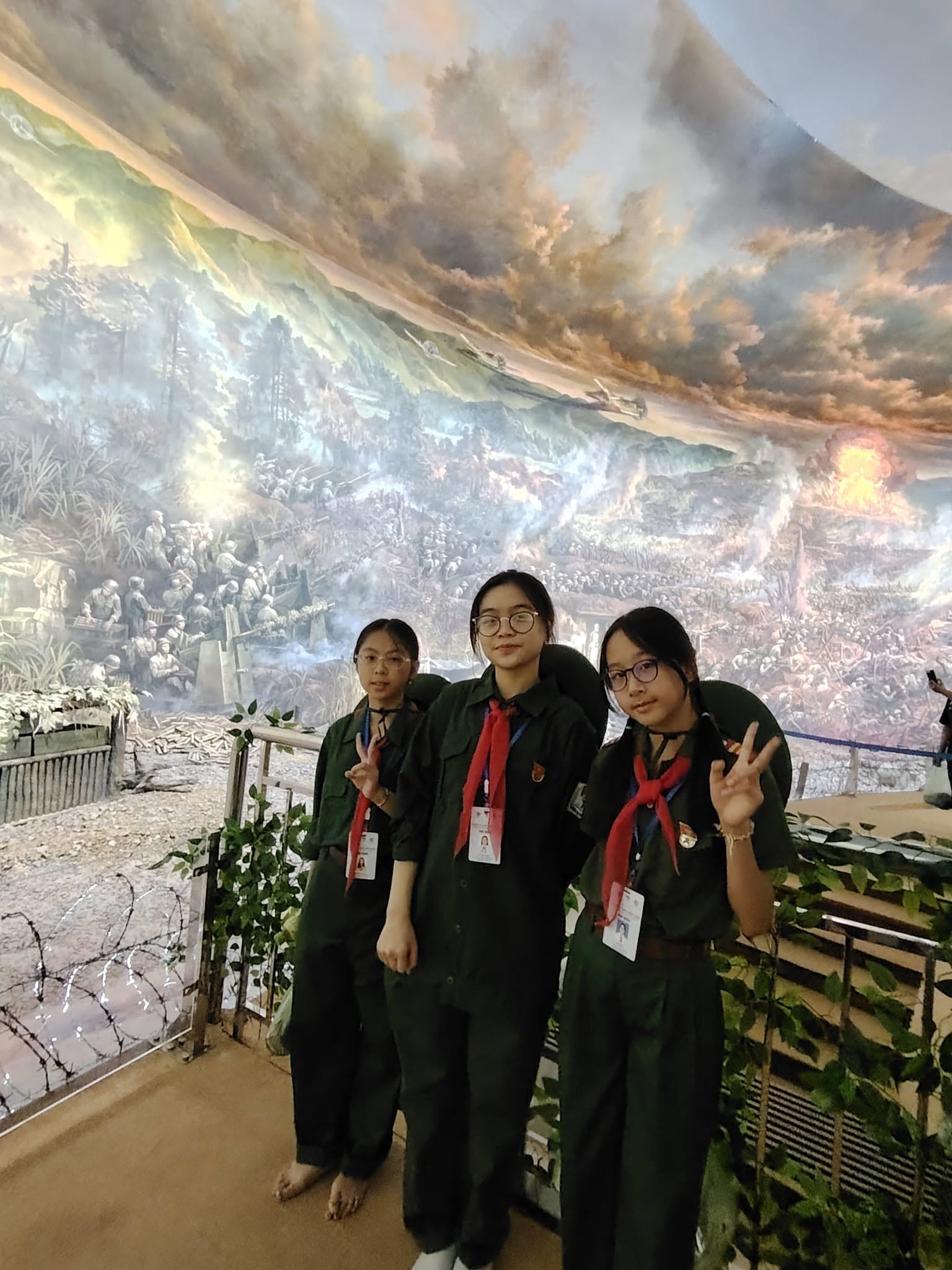 3 đại biểu thiếu nhi cùng chụp ảnh với bức tranh panorama tái hiện toàn cảnh chiến dịch Điện Biên Phủ.jpg