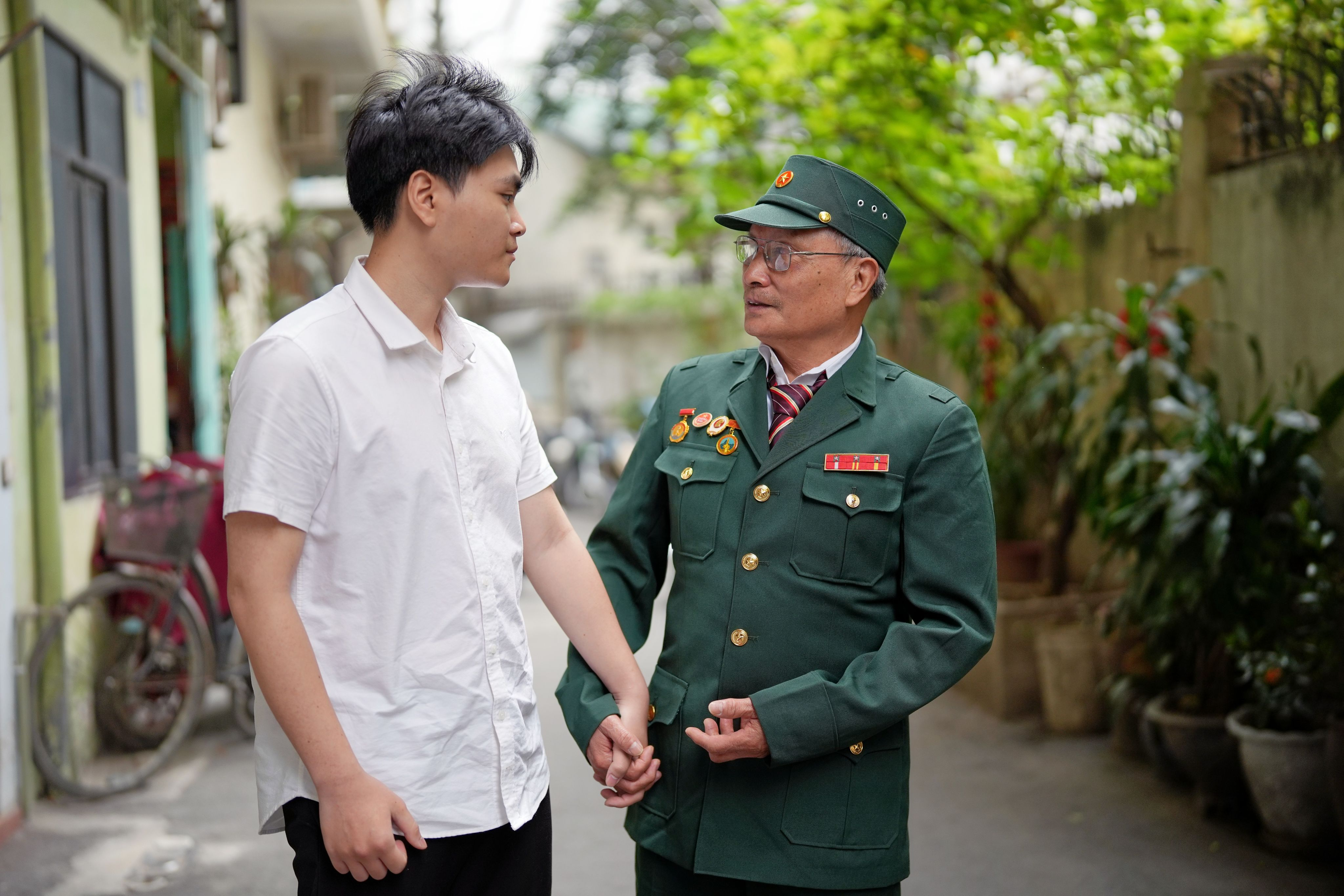 Hai ông cháu bước chậm trong con ngõ nhỏ, nắng tháng Tư rót vàng trên vai.